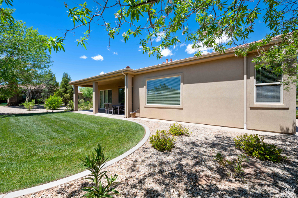 Rear view of property with a lawn, stucco siding, and a patio area