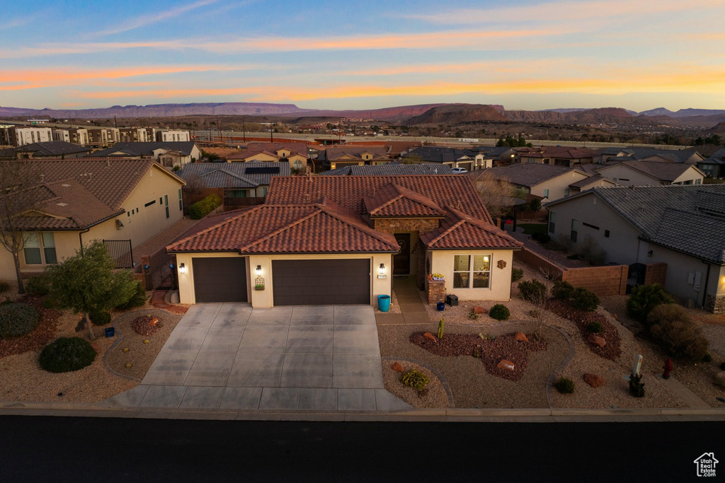 Mediterranean / spanish-style house with a residential view, driveway, a garage, and stucco siding