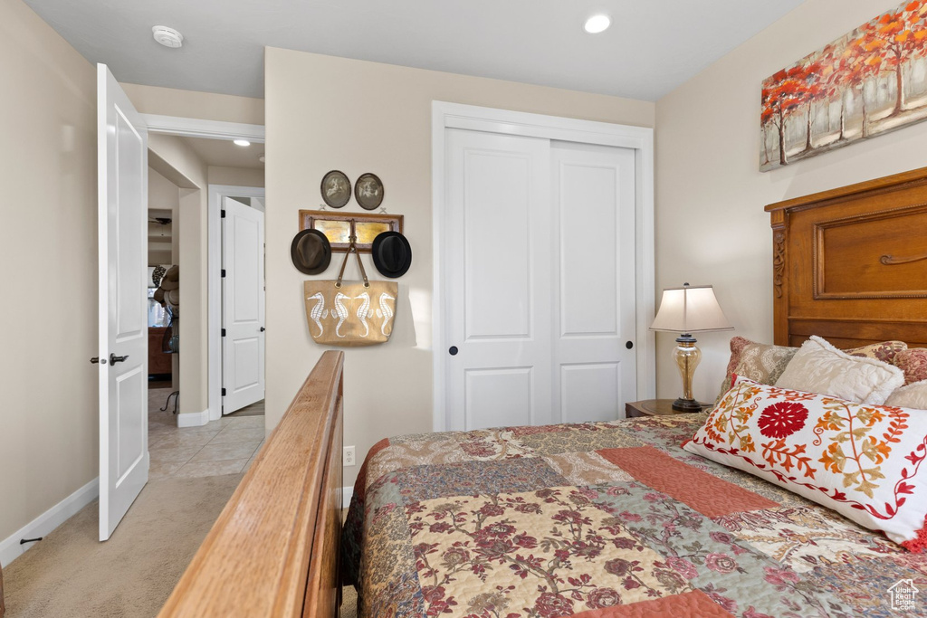 Bedroom with baseboards, recessed lighting, light colored carpet, and a closet