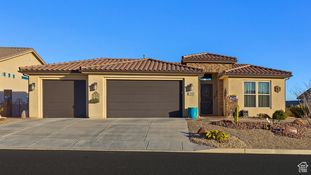 View of front facade featuring a garage, stucco siding, driveway, and a tiled roof