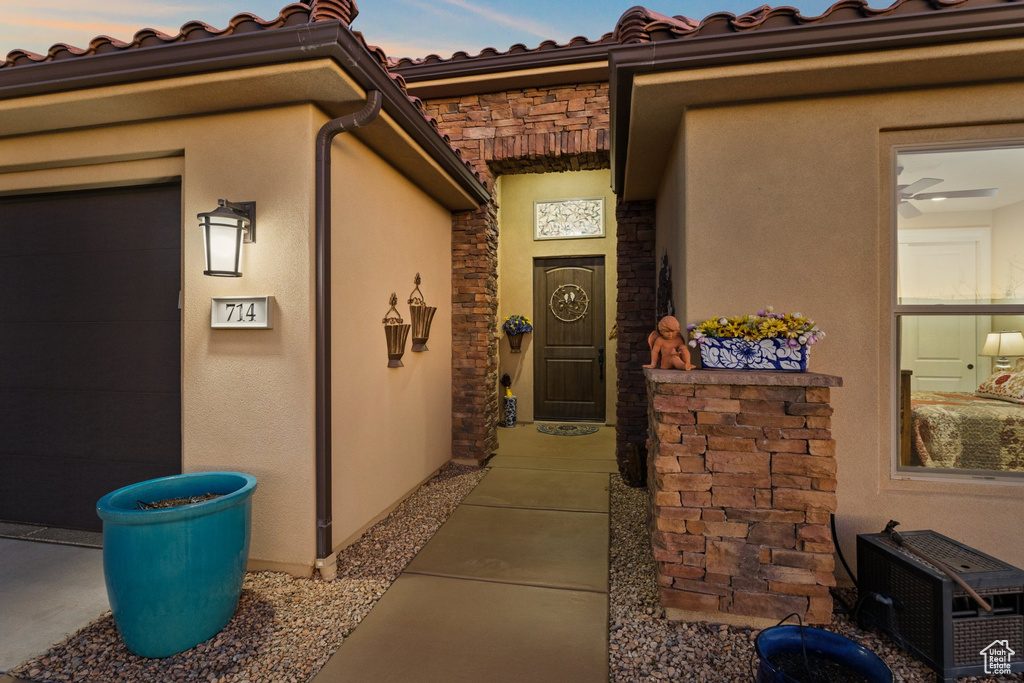 Doorway to property with stucco siding, a tiled roof, and stone siding