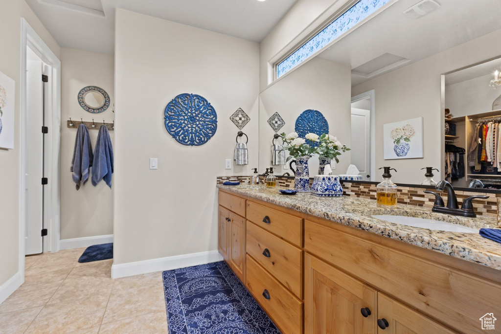 Bathroom with a sink, tile patterned floors, double vanity, baseboards, and a spacious closet