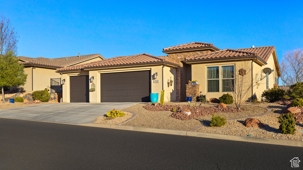 Mediterranean / spanish home with a tile roof, concrete driveway, a garage, and stucco siding