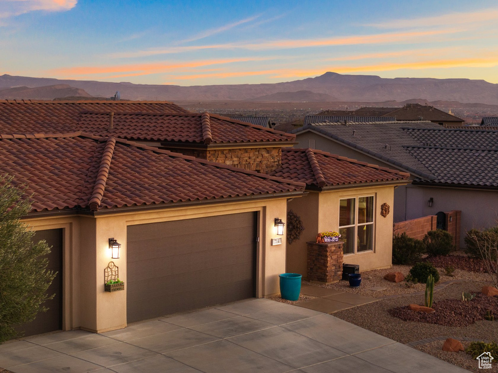 Mediterranean / spanish-style home with driveway, a tiled roof, a mountain view, an attached garage, and stucco siding
