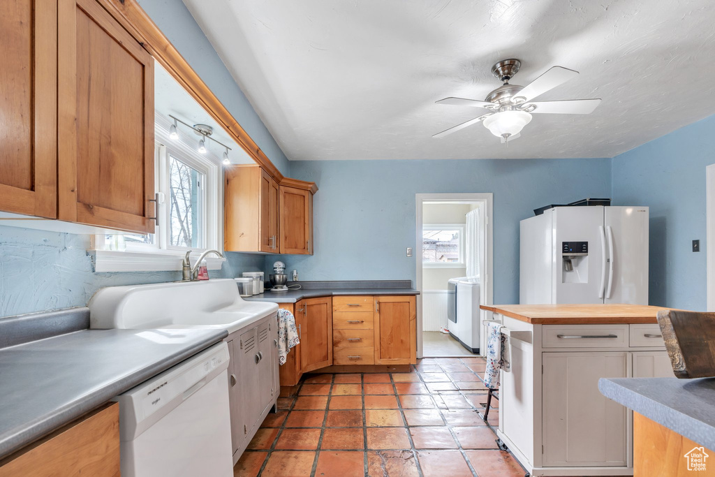 Kitchen featuring a sink, wooden counters, washer / dryer, white appliances, and ceiling fan