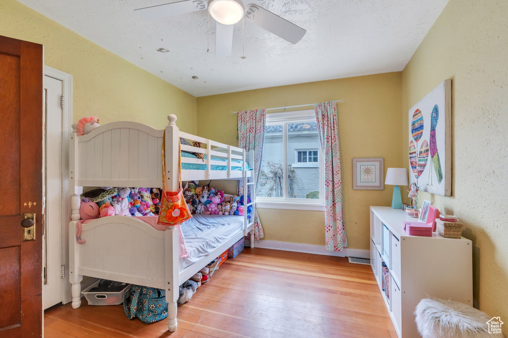 Bedroom with visible vents, hardwood / wood-style flooring, baseboards, a ceiling fan, and a textured wall