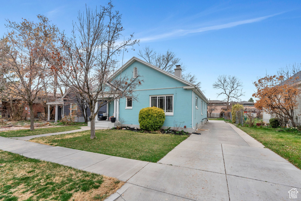 Bungalow-style home featuring a chimney and a front lawn