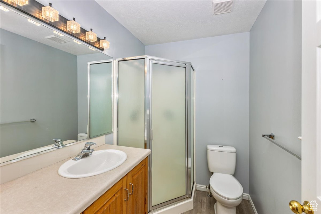 Full bathroom featuring vanity, toilet, baseboards, a shower stall, and visible vents