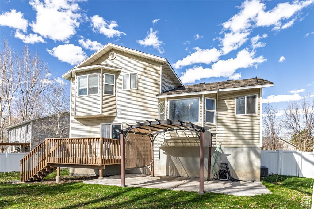 Back of house featuring a pergola, fence, a patio, and a lawn