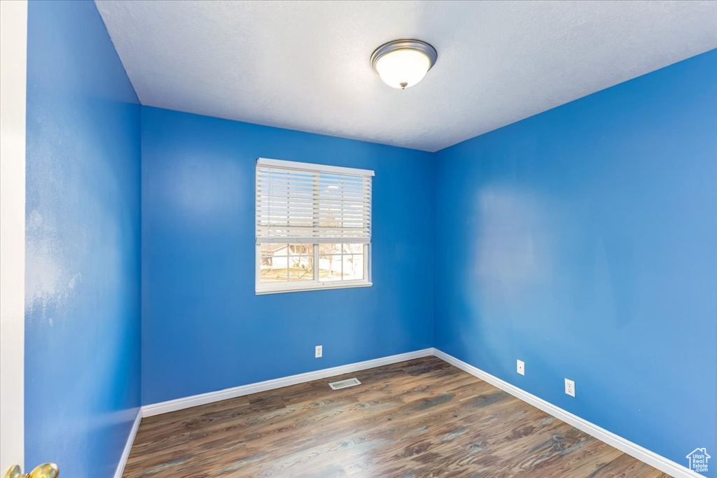 Empty room featuring baseboards, visible vents, and wood finished floors
