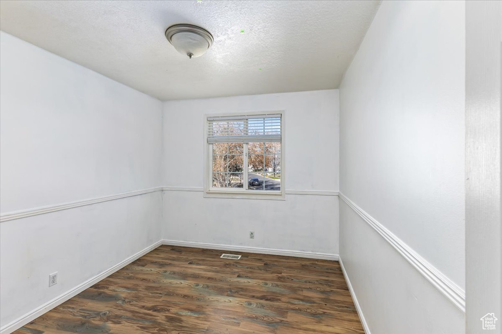 Empty room with baseboards, visible vents, a textured ceiling, and wood finished floors