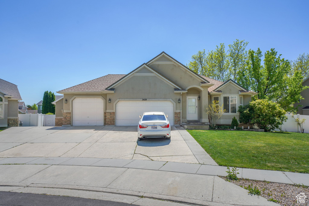 Single story home with an attached garage, concrete driveway, stucco siding, and stone siding
