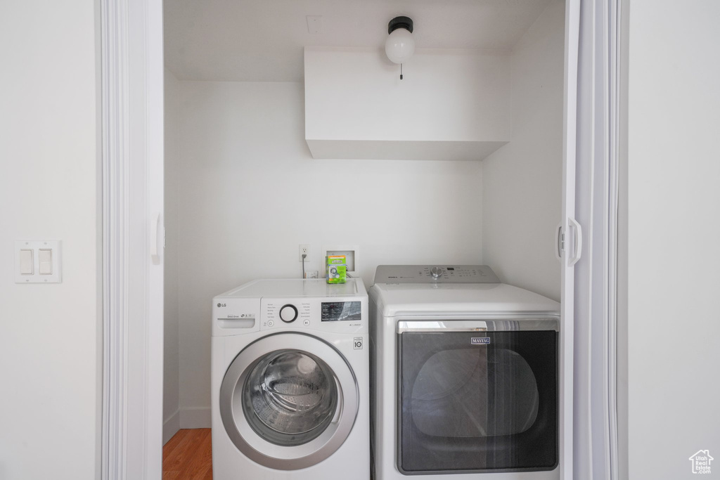 Washroom with washing machine and dryer and wood finished floors