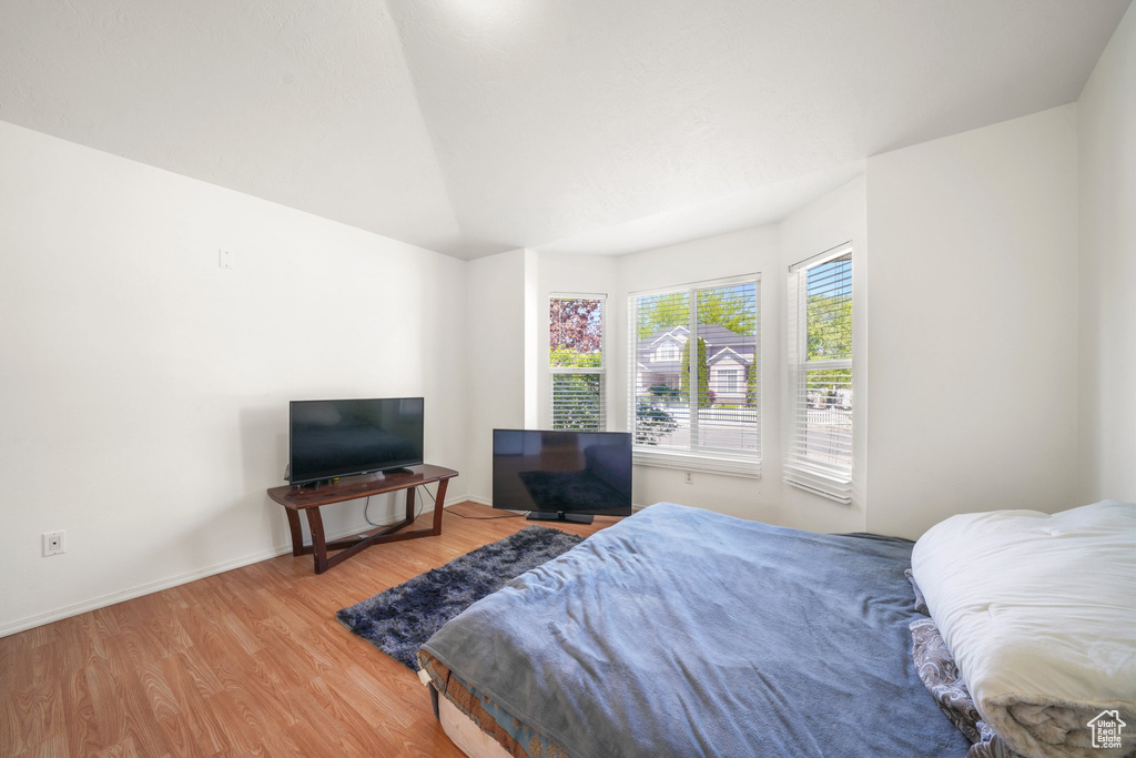 Bedroom with wood finished floors, baseboards, and lofted ceiling