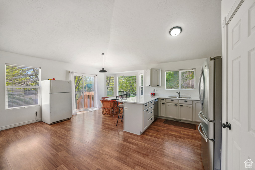 Kitchen with appliances with stainless steel finishes, a peninsula, a sink, dark wood-style flooring, and plenty of natural light