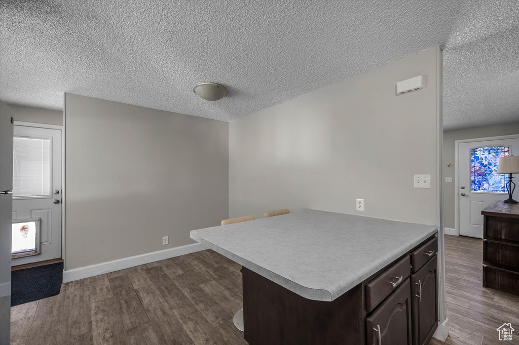Kitchen with light countertops, baseboards, a textured ceiling, dark wood-style floors, and dark brown cabinets