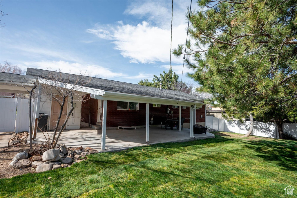 Back of house featuring a lawn, brick siding, fence private yard, and a patio area