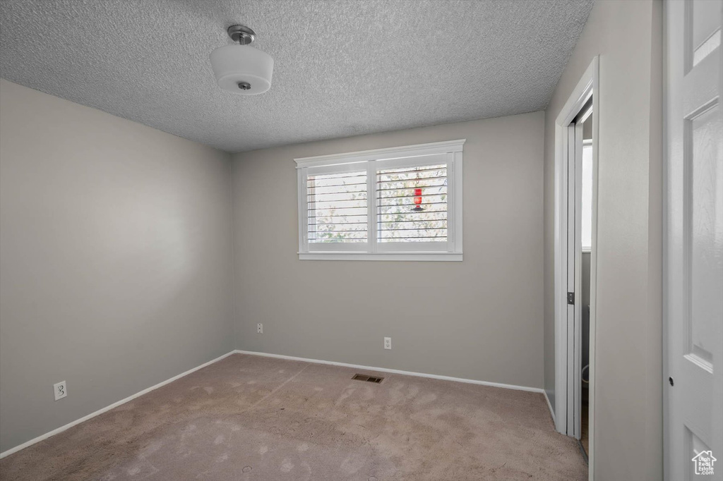 Unfurnished bedroom with baseboards, carpet flooring, a textured ceiling, and visible vents