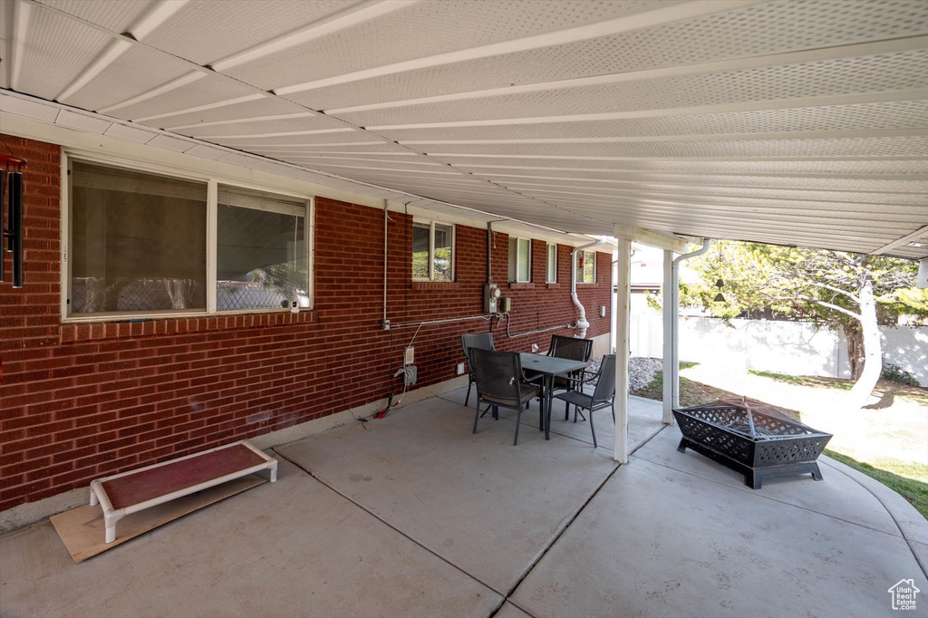 View of patio featuring outdoor dining area, a fire pit, and fence