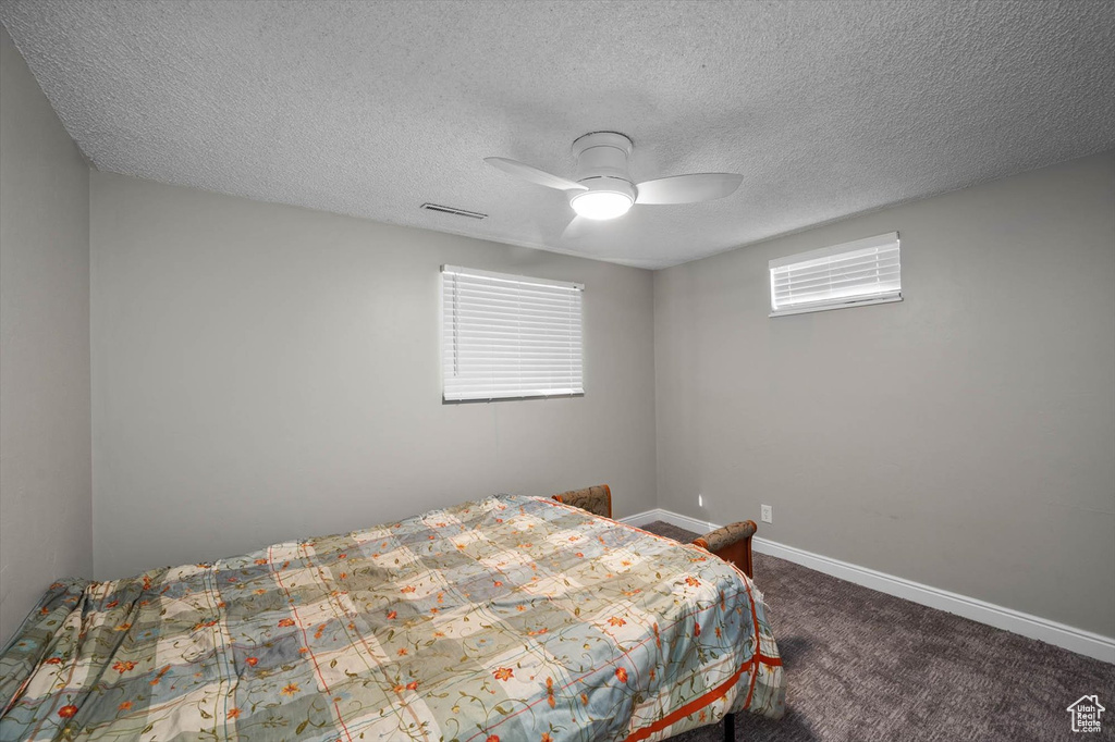 Carpeted bedroom with baseboards, a textured ceiling, ceiling fan, and visible vents