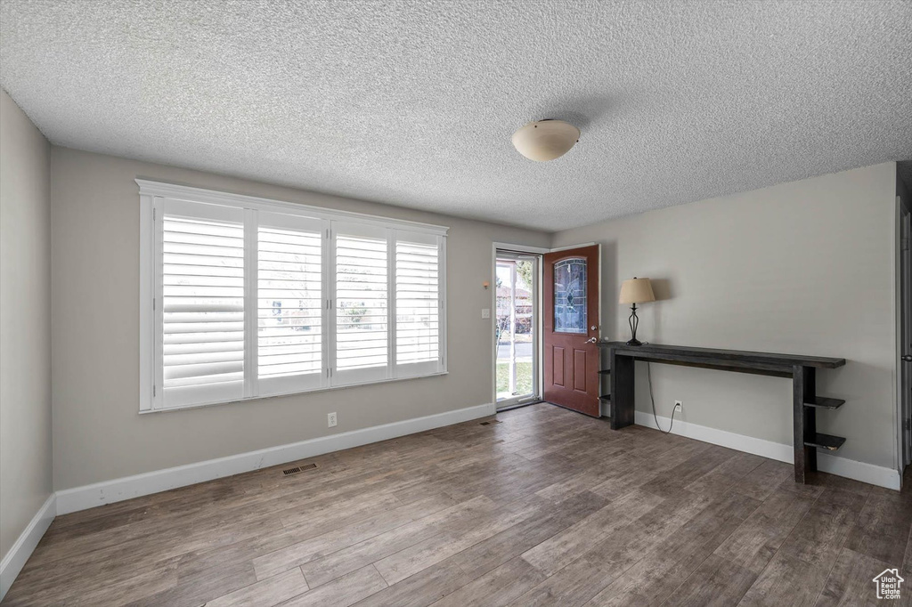 Entryway with dark wood-style floors, visible vents, baseboards, and a textured ceiling