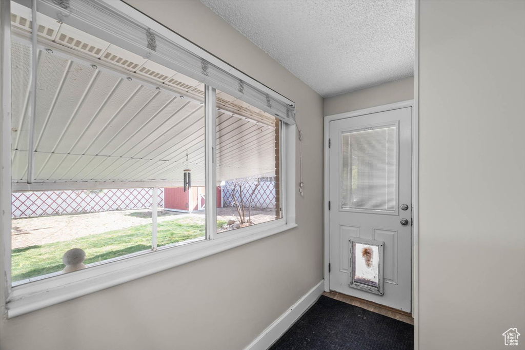 Doorway to outside with baseboards and a textured ceiling