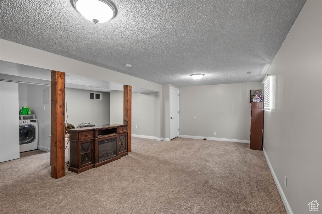 Finished basement with baseboards, carpet flooring, a textured ceiling, and washer / dryer