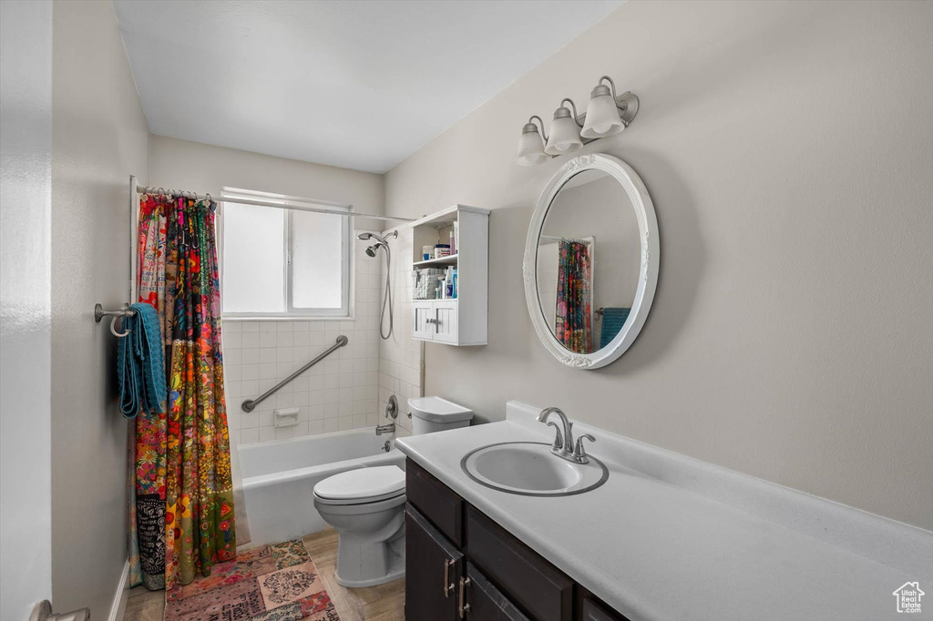 Bathroom with toilet, shower / bathtub combination with curtain, and vanity