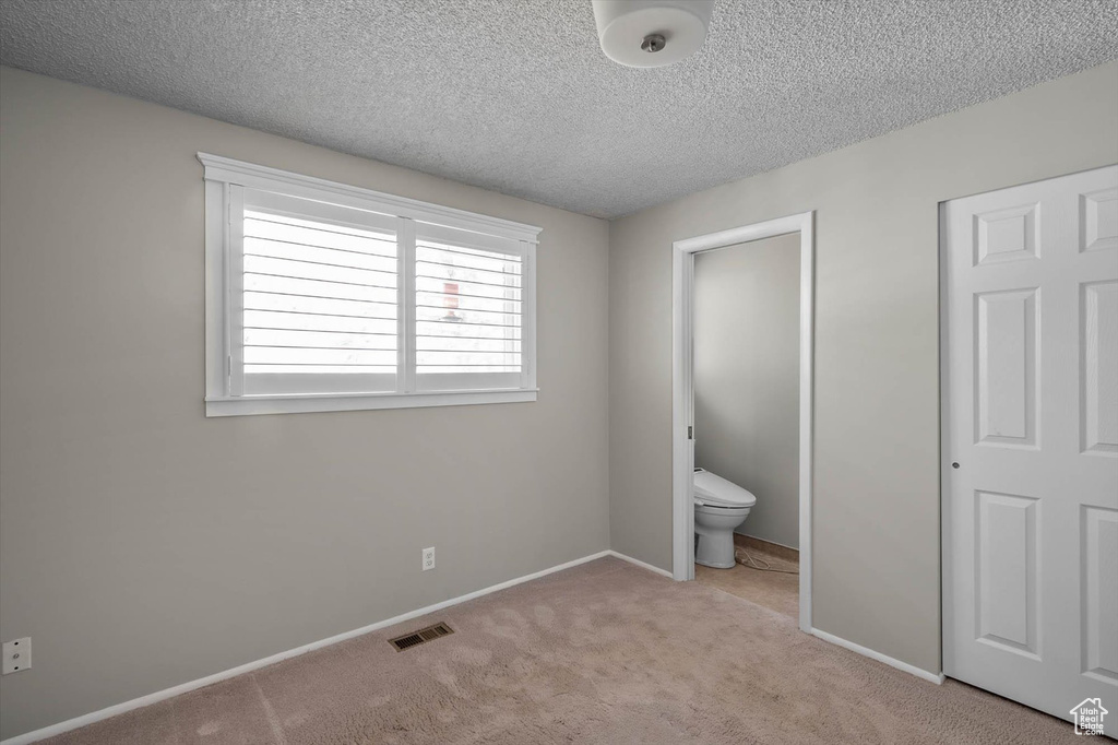 Unfurnished bedroom featuring baseboards, a textured ceiling, visible vents, and carpet