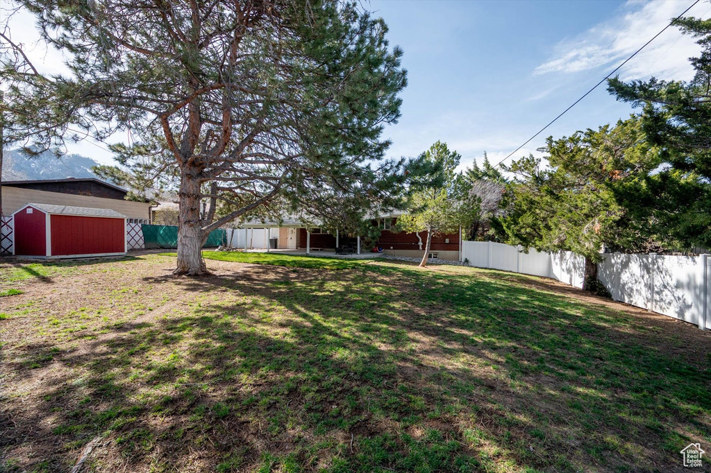 View of yard with a fenced backyard, an outbuilding, a storage unit, and a patio
