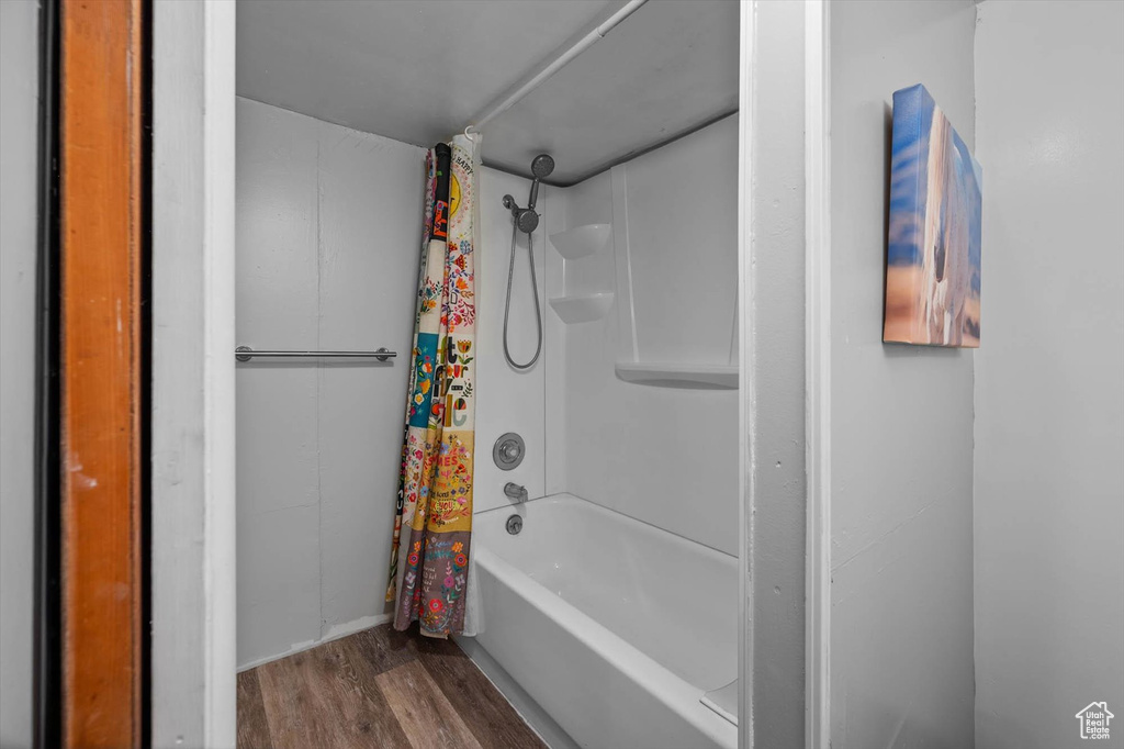 Full bath with wood finished floors and shower / bath combination with curtain