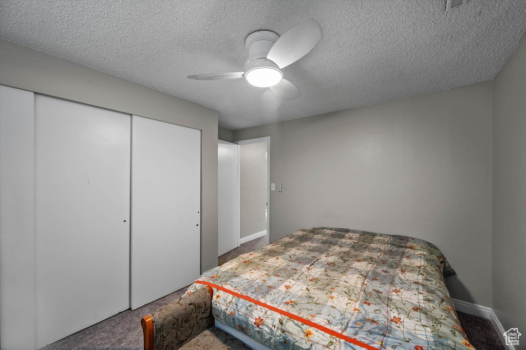 Bedroom featuring a ceiling fan, a closet, carpet, and a textured ceiling