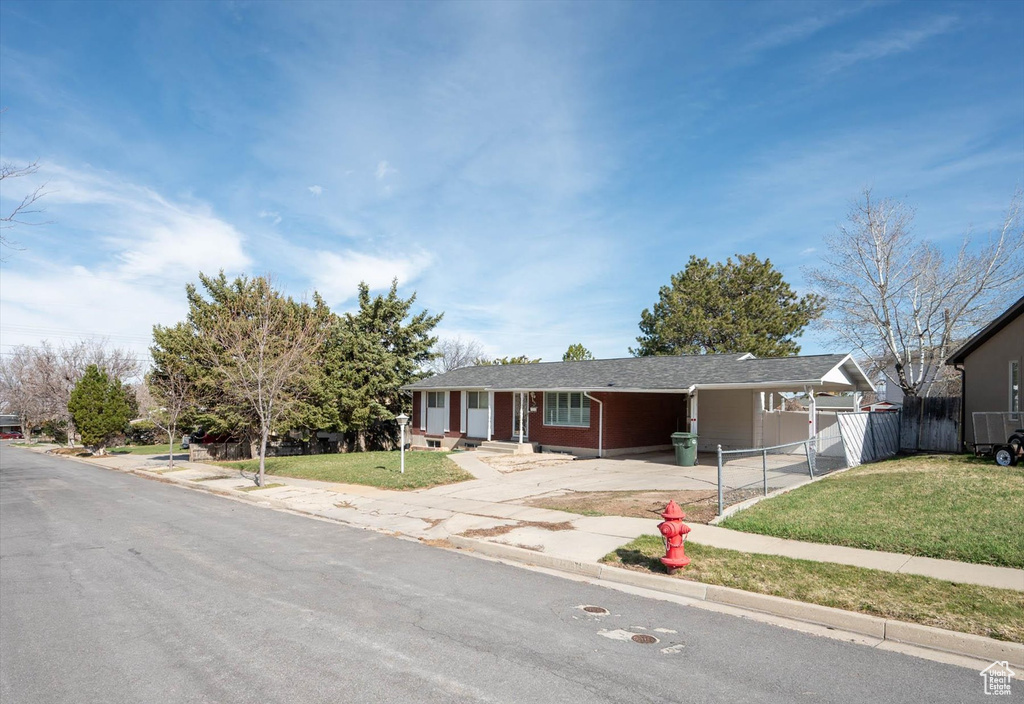 Ranch-style home featuring an attached carport, a front yard, fence, and driveway