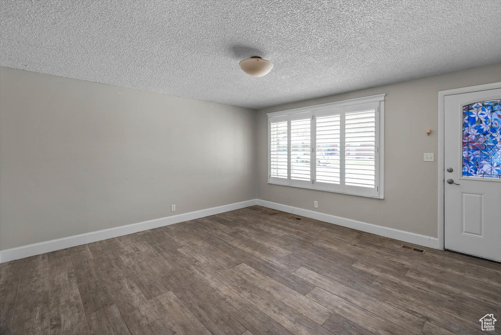 Foyer featuring dark wood-style floors, baseboards, a textured ceiling, and visible vents