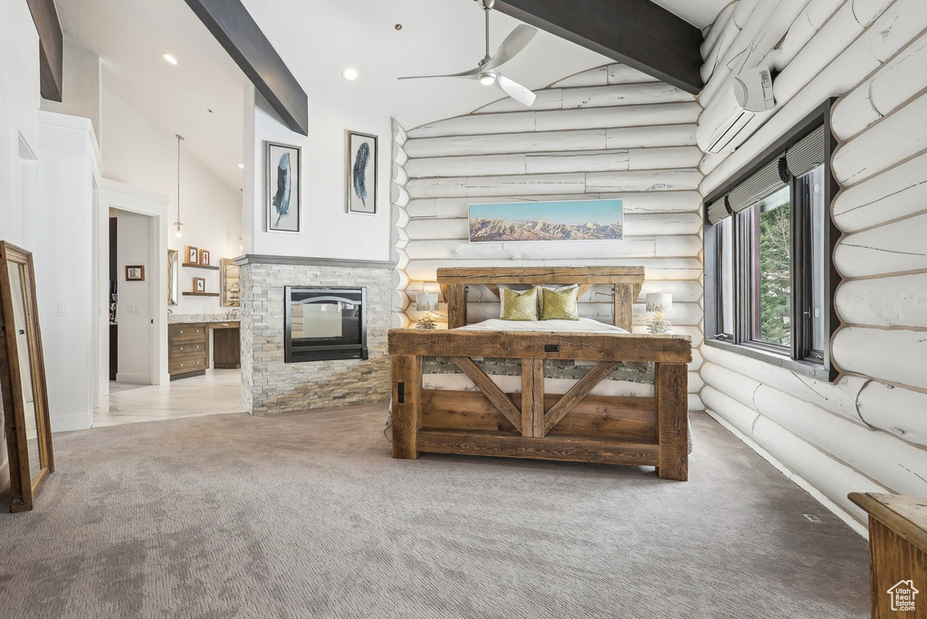 Carpeted bedroom with a stone fireplace, rustic walls, beamed ceiling, high vaulted ceiling, and a wall mounted AC
