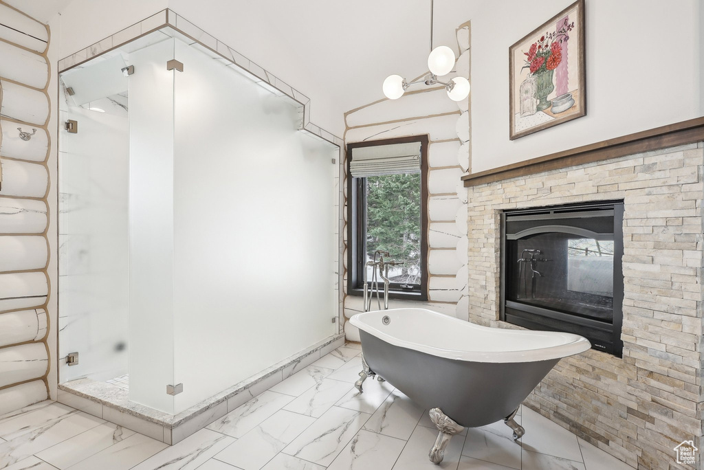 Bathroom with marble look tiles, a stall shower, a freestanding tub, and a stone fireplace
