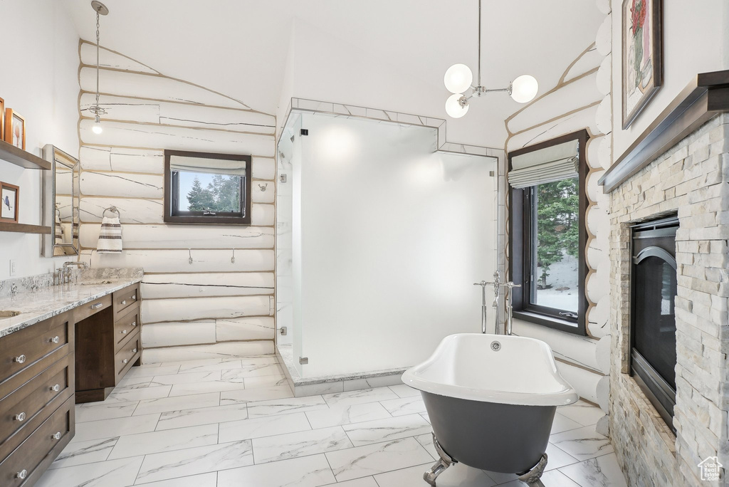 Bathroom with marble finish floors, vanity, a freestanding tub, a glass covered fireplace, and a high ceiling