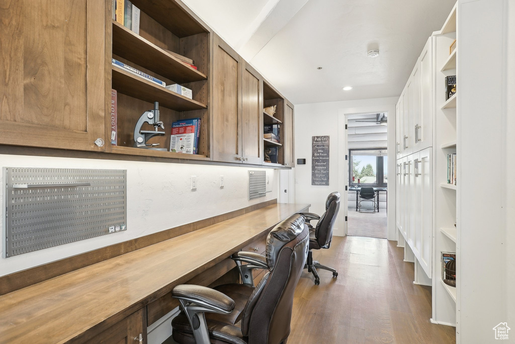 Home office featuring wood finished floors, built in shelves, and recessed lighting