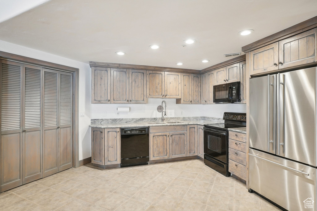 Kitchen with black appliances, a sink, light stone countertops, recessed lighting, and light tile patterned flooring