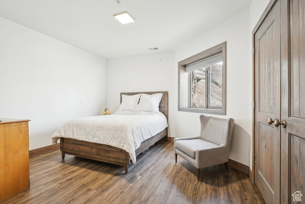 Bedroom with wood finished floors, baseboards, and a closet