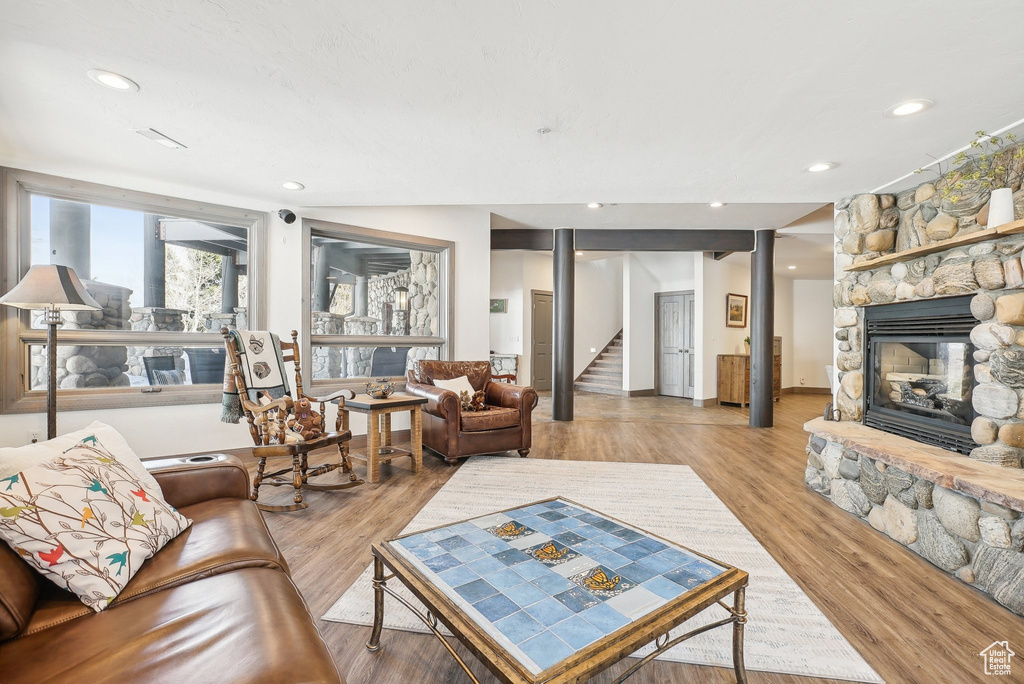 Living area with stairs, a stone fireplace, light wood-type flooring, and recessed lighting
