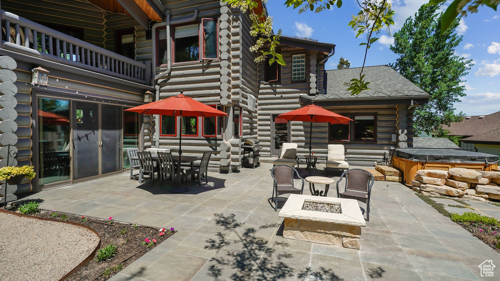 View of patio / terrace with a hot tub, a balcony, an outdoor fire pit, and outdoor dining area