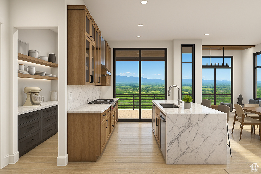 Kitchen featuring a sink, light stone counters, recessed lighting, brown cabinets, and light wood-type flooring