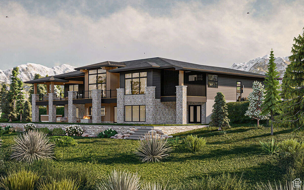 Back of house with a balcony, a mountain view, and a lawn