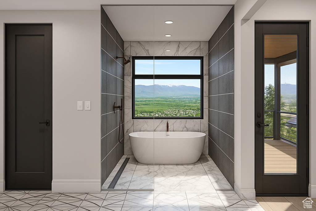 Full bath with a freestanding tub, tile walls, recessed lighting, marble finish floors, and a mountain view