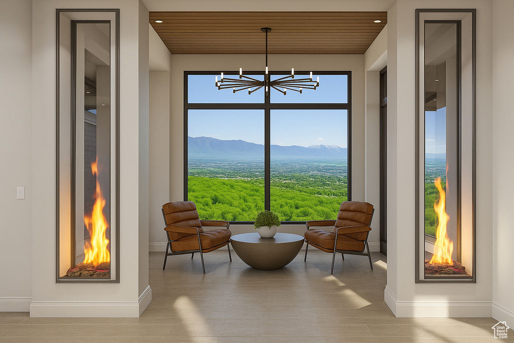 Living area featuring baseboards, a chandelier, a mountain view, wood ceiling, and wood finished floors
