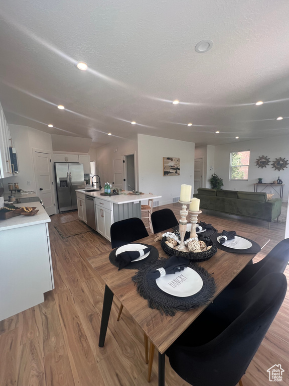Dining room with light wood-style flooring, recessed lighting, and a textured ceiling