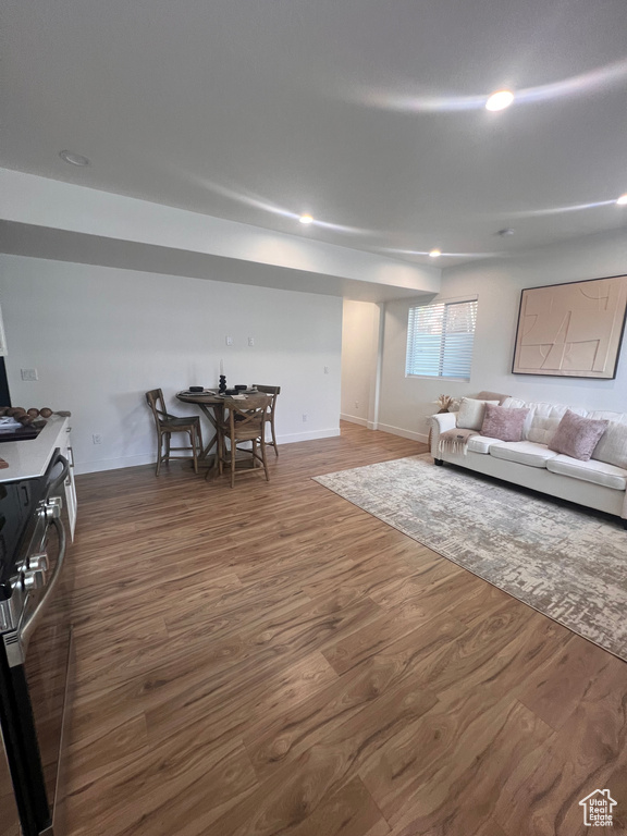 Living area with dark wood-type flooring, recessed lighting, and baseboards