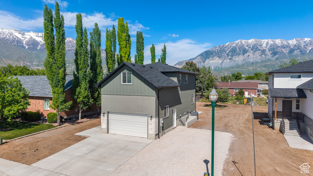 View of front facade featuring a mountain view, concrete driveway, a garage, and board and batten siding