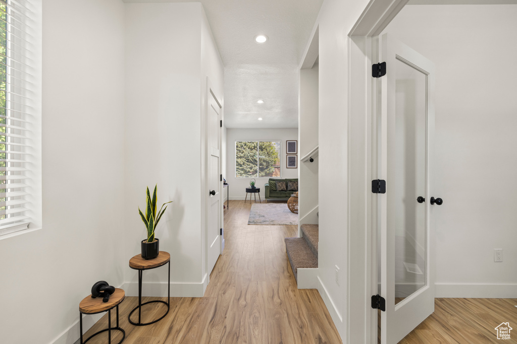 Hall with baseboards, light wood-style flooring, and recessed lighting